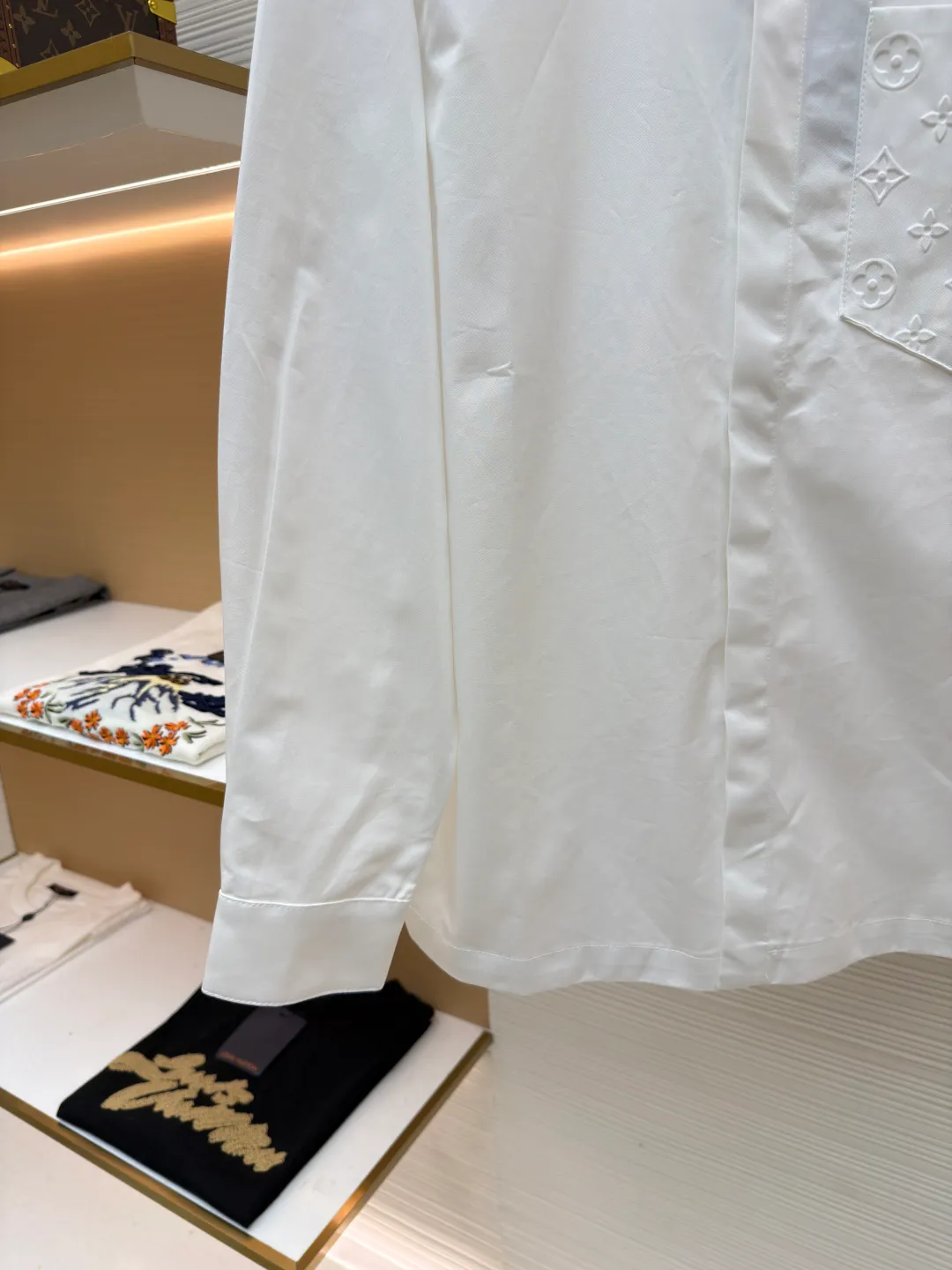 LOUIS VUITTON Embossed Pocket Lapel Shirt ●Original version: Purchased and developed for 3989 ●Item number: 1681491-B05 ●Fabric: Cotton twill woven fabric ●Technology: Concave embossed printing ●Color: white ●Version: Fitted version ●Weight: about 370 grams ●Size: XS-S-M-L ●Description: The twill pattern is obvious on the front of the fabric and blurry on the reverse. Single yarn is used in both warp and weft directions, and the linear density is close. The warp density of the fabric is slightly higher than the weft density, and the hand feel is relatively soft. The fabric has excellent stability, is not easy to deform, and prevents bulging; cotton fiber has good hygroscopicity, which keeps the fabric in a water balance, making people feel comfortable, and adding to the sophistication of the fabric. The concave and convex embossing process is formed by heating and shaping the upper and lower dies. The rollers press the fabric at a certain temperature, and the three-dimensional hierarchical convex surface is produced through mechanical embossing. The fabric produces a concave and convex pattern with a relief-style three-dimensional effect and a special gloss effect. The three-dimensional shape, pattern and text have a strong three-dimensional sense, adding a decorative art effect, clear layers, concentrated three-dimensional image, and accurate perspective angle. The collar can be adjusted with buttons for both formality and comfort; the pleats and tabs at the back are classic shirting techniques, with the pleats providing extra room for movement and the tabs keeping the shirt in shape when hanging. The button front uses custom-fit buttons that are positioned accordingly, and together these details ensure the shirt's functionality and crisp look. The overall wiring is straight and delicate, the fabric is comfortable and soft, and the color is consistent without color difference. It can be matched with the same style to create a fashionable look and control various occasions. Customized accessories, complete with three standards, same style for men and women!